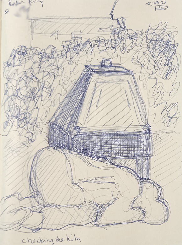 A quick sketch of a potter kneeling on the ground as she checks underneath a kiln that is doing a raku firing. She kneels in front of the kiln, with a leafy hedge behind the kiln. 
